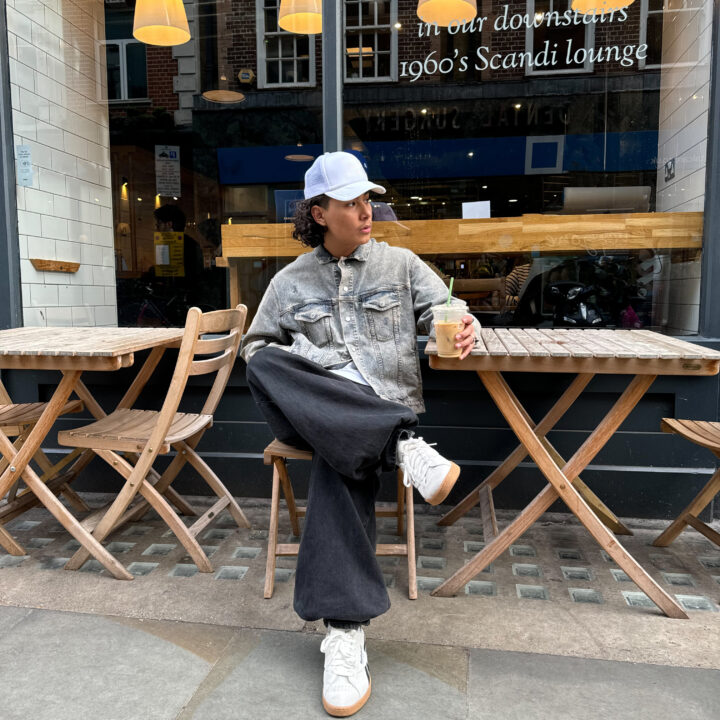 Person sat outside coffee shop with white reebok trainers