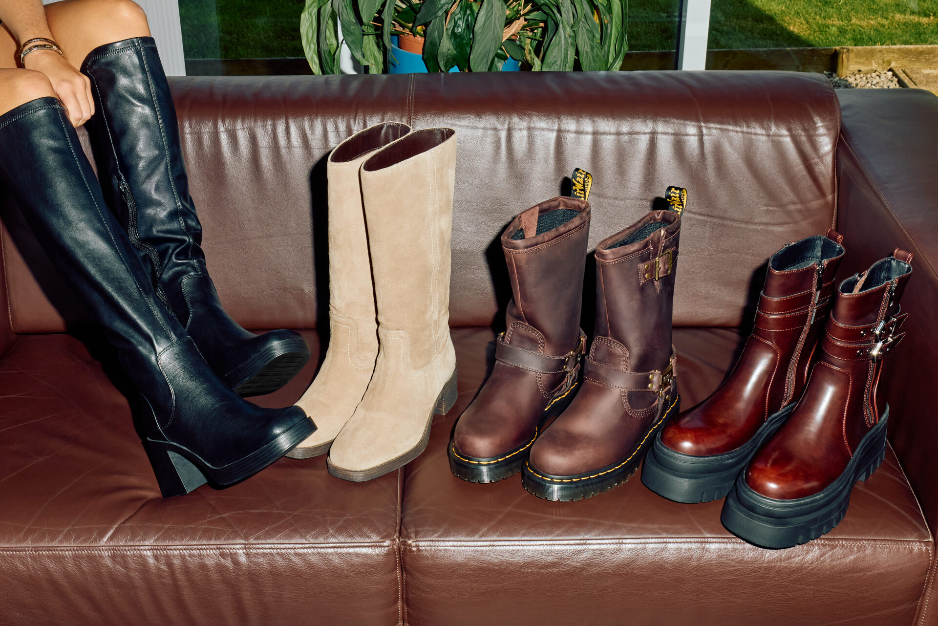 Four pairs of boots, two knee high and two moto, in different shades of brown and black.