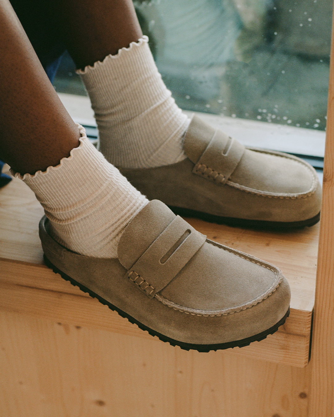 Person wearing beige BIRKENSTOCK Naples with white socks.