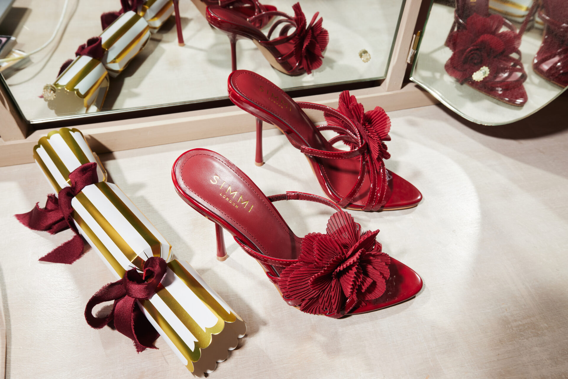 A pair of the SIMMI Millie Flowers in burgundy next to a Christmas cracker.