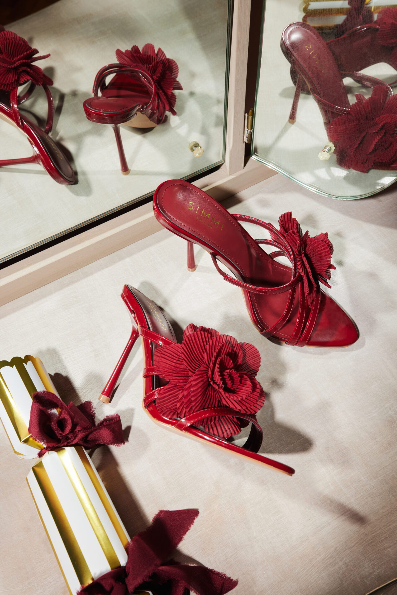 A pair of the SIMMI Millie Flowers in burgundy next to a Christmas cracker.