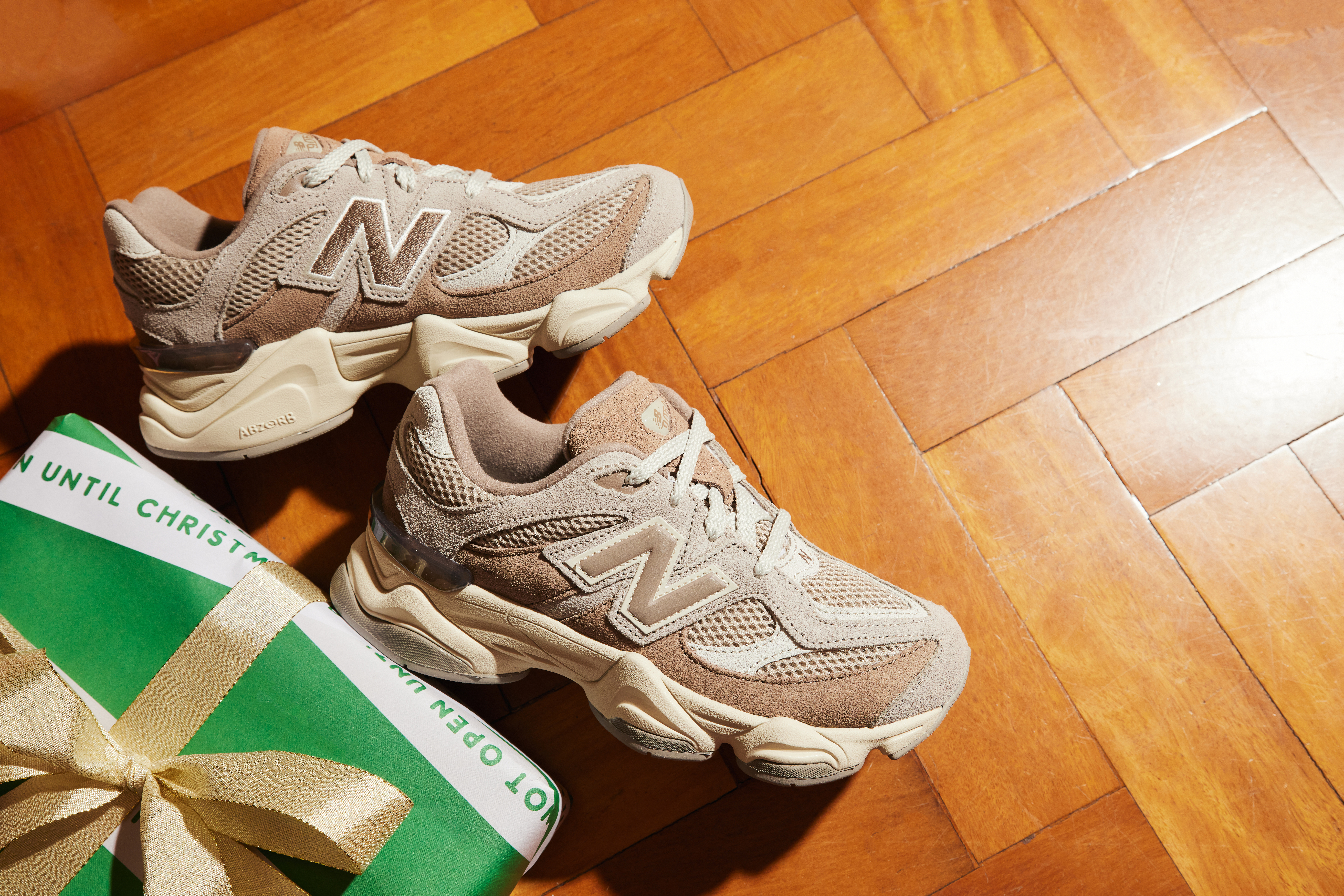 A pair of New Balance 9060s in beige next to a wrapped present.