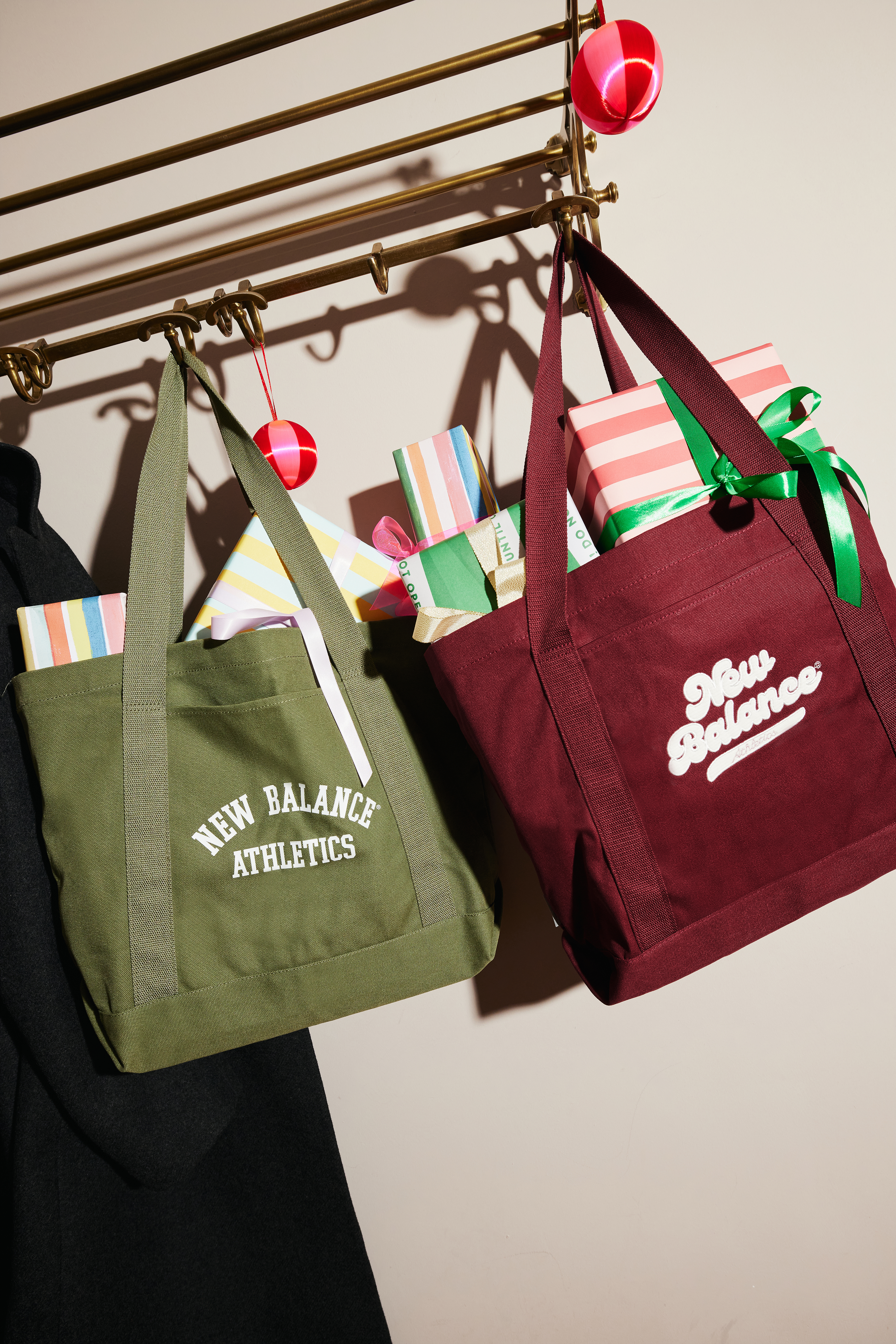 A green New Balance tote bag and a burgundy one, both filed with presents.