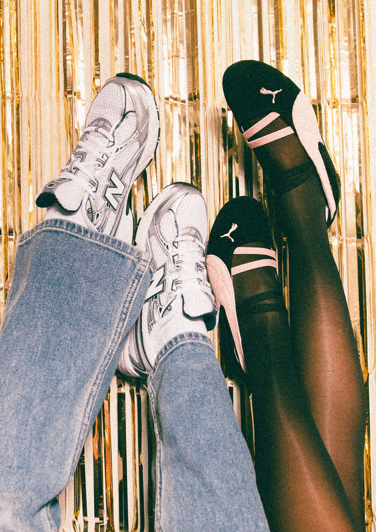Someone wearing white New Balance 530s with jeans and someone wearing black & pink PUMA Speedcat Ballets with tights, against a festive ribbon background.