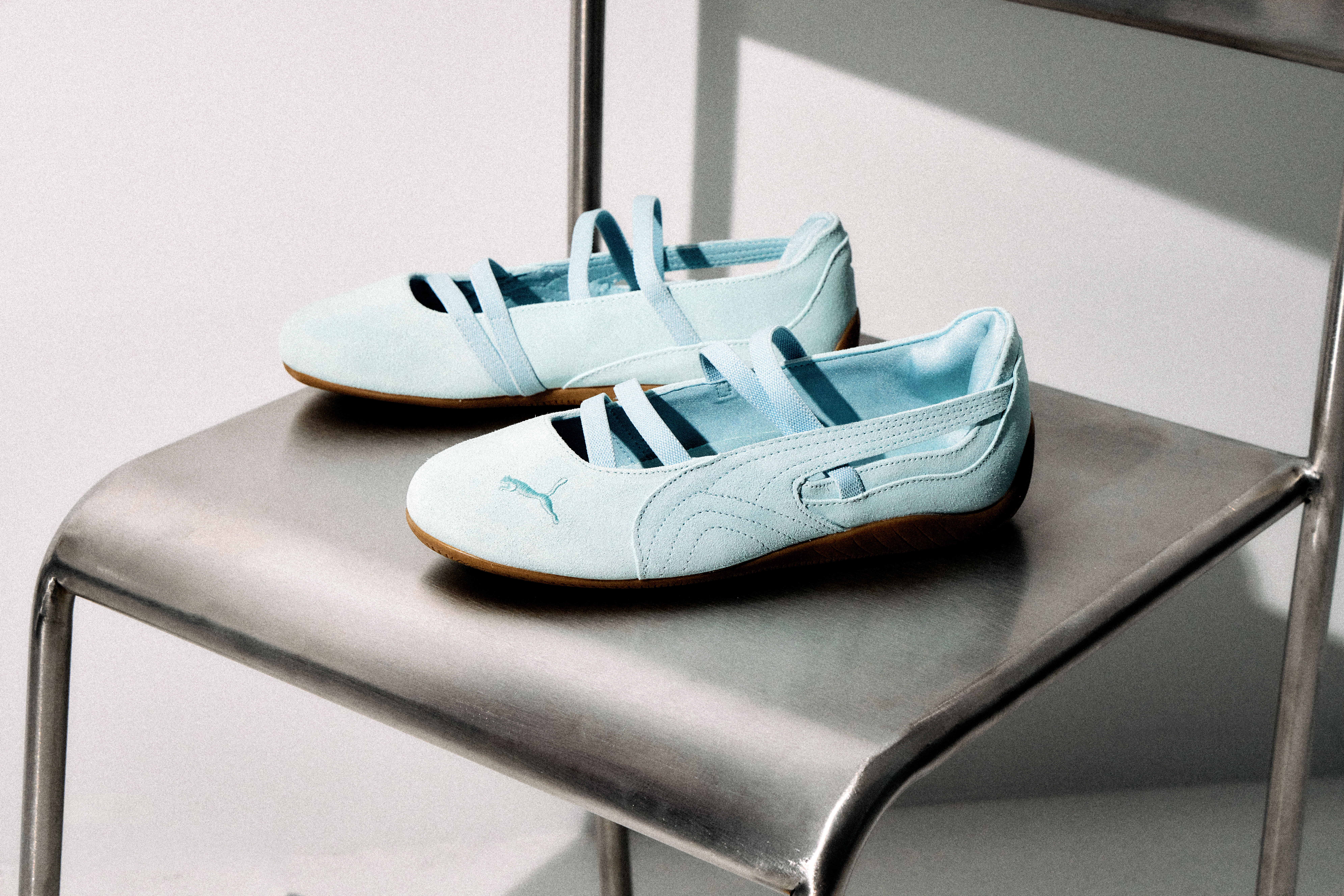 A pair of pale blue PUMA Speedcat Ballet on a metal chair.