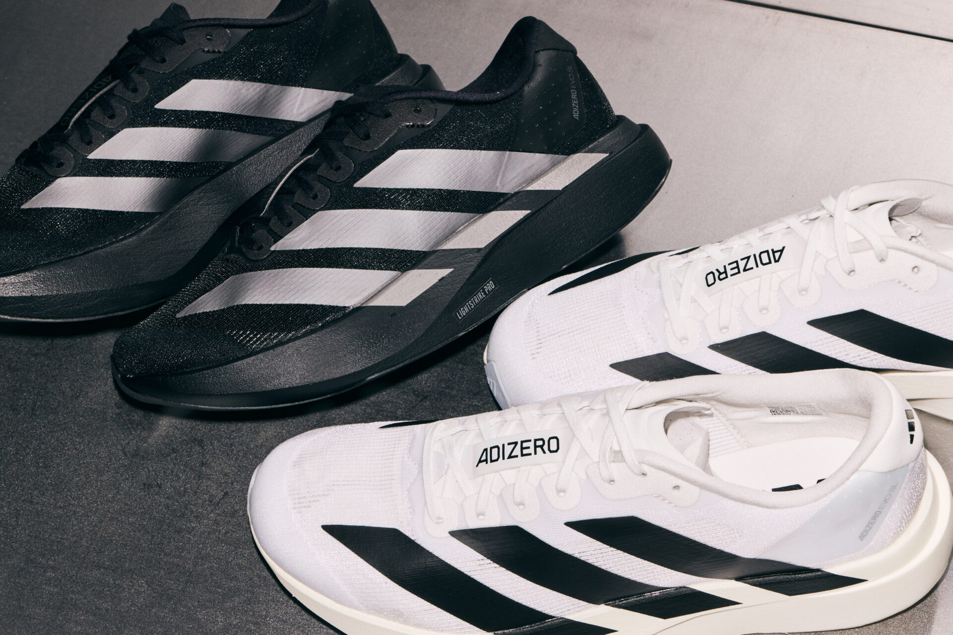 Two pairs of adidas Adizero EVO SL trainers: one in black & silver and one in white & black.