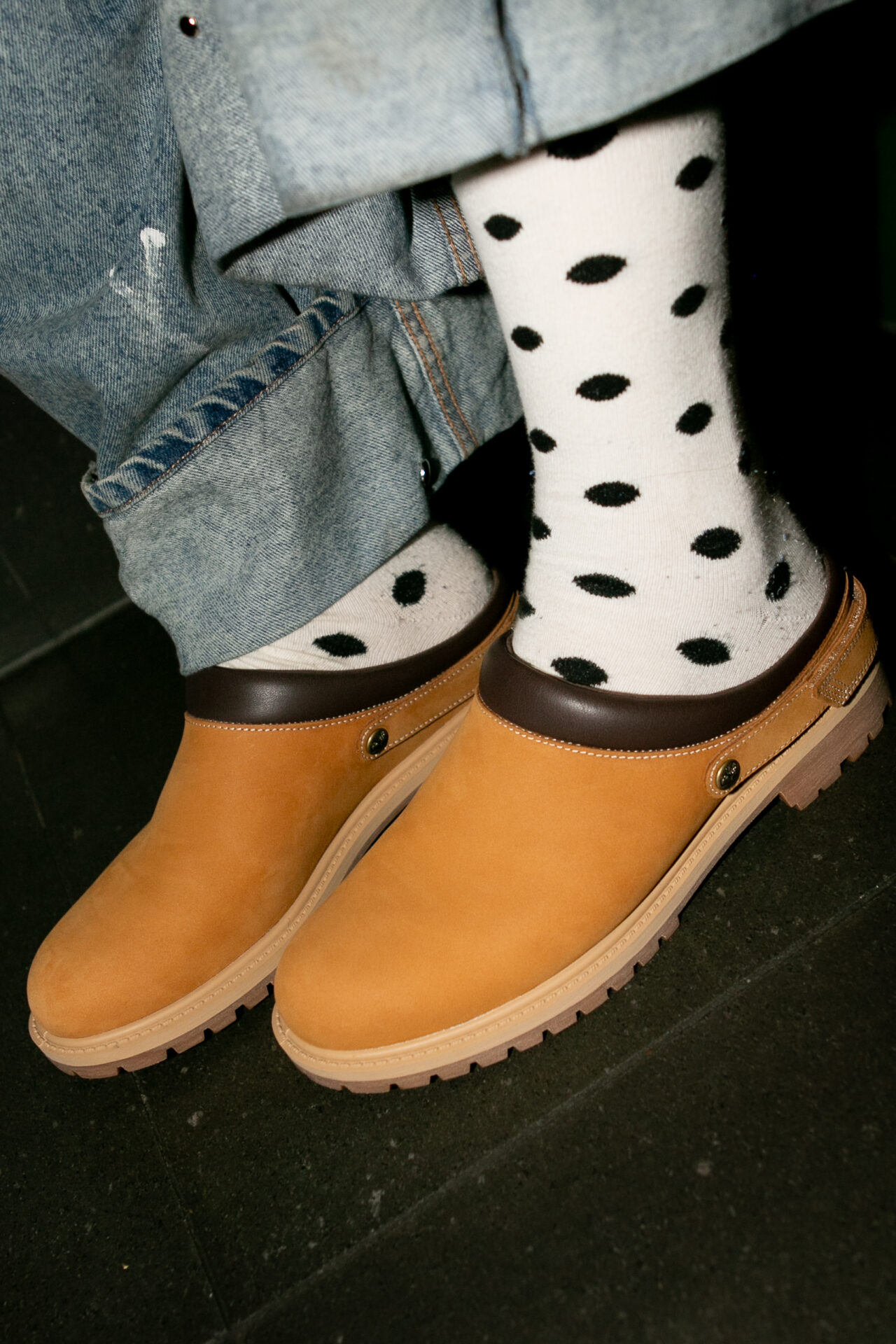 Person wearing the Timberland Premium Clog in Tan with spotty white and black socks and wide leg light blue jeans.