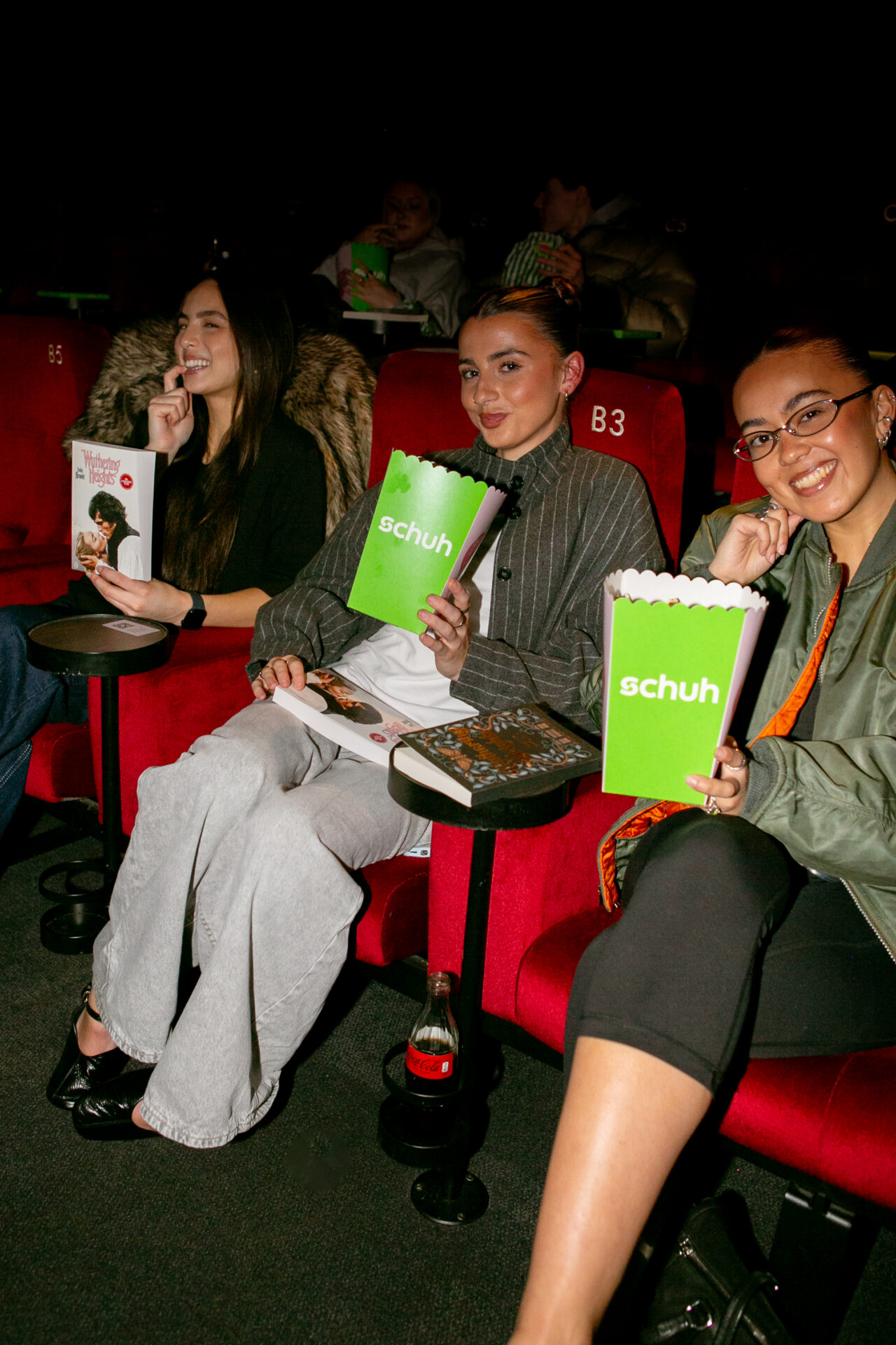 Three guests at the screening with schuh branded popcorn and copies of the Wuthering Heights novel.