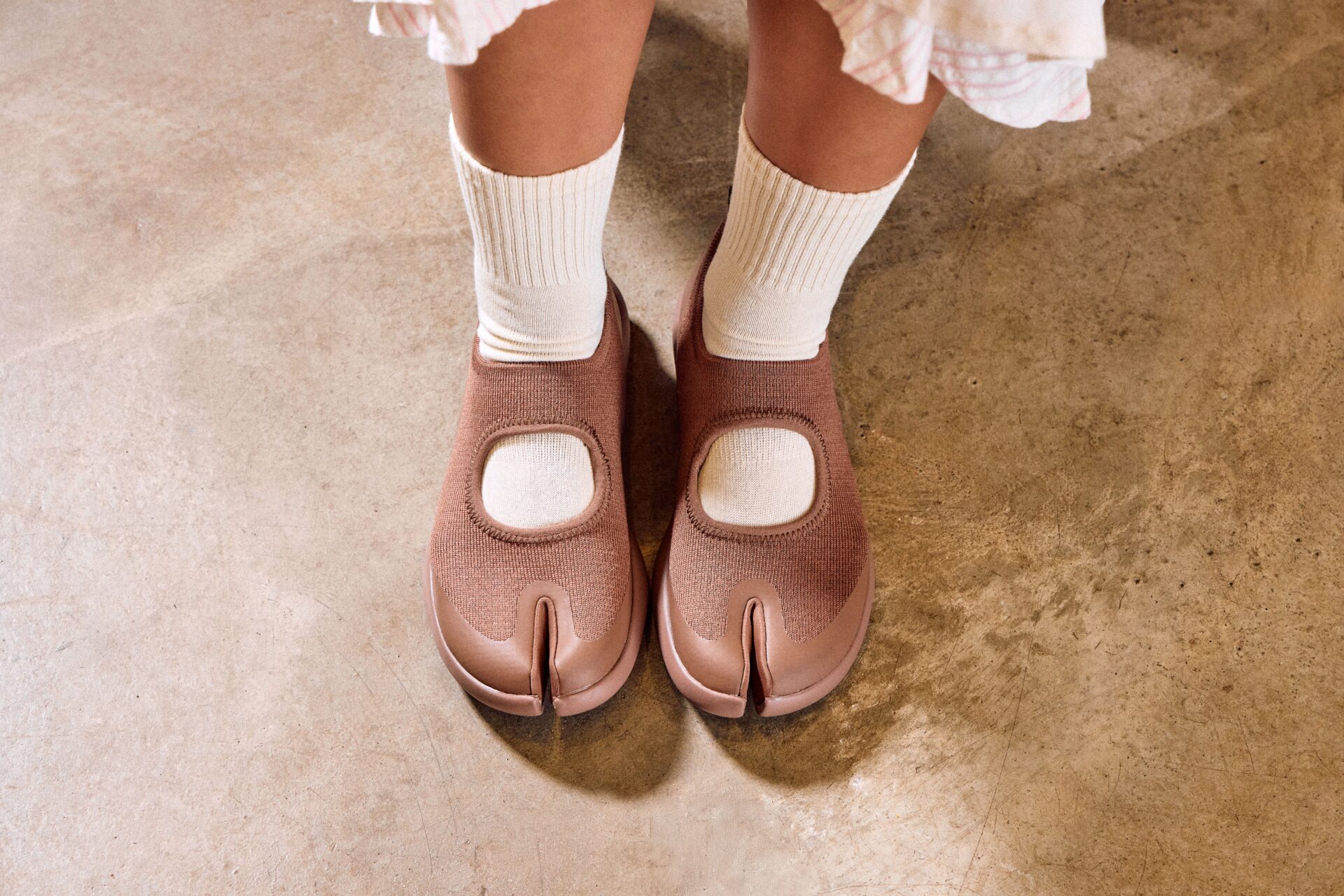 Person wearing TABI trainer in brown with white socks.