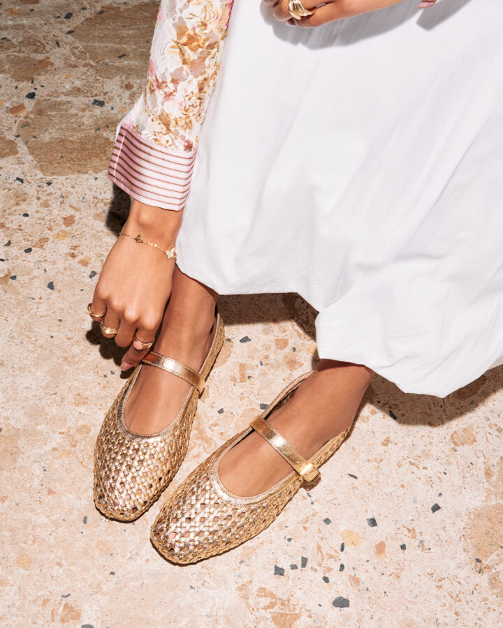 Person wearing schuh Lexie Woven Ballerina in gold with a white maxi skirt and floral blouse.