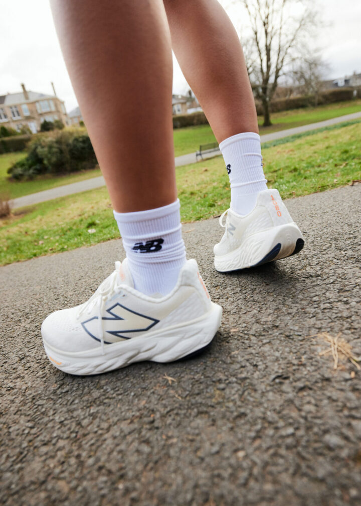 Person standing outside wearing off-white New Balance running shoes paired with white New Balance socks.