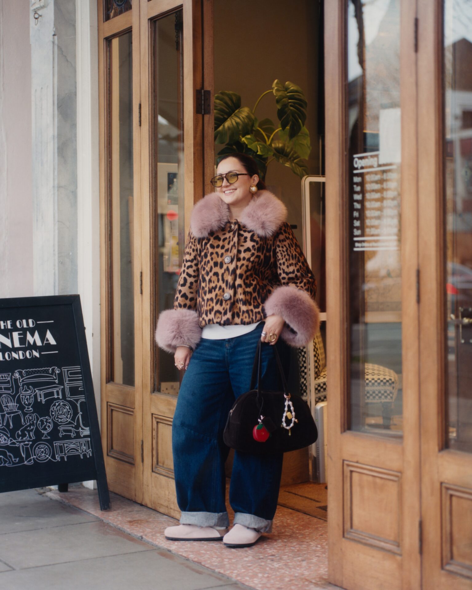 Nelle Studios founder Grace Lotti standing at a shop entrance wearing the BIRKENSTOCK Boston in pink with blue jeans, a leopard print coat with furry collars, and sunglasses.