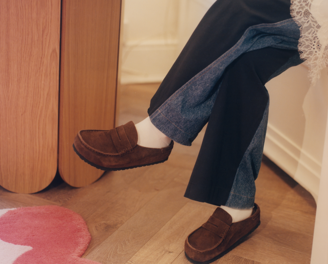 Person wearing the BIRKENSTOCK Naples in brown with white socks and two-toned blue jeans.