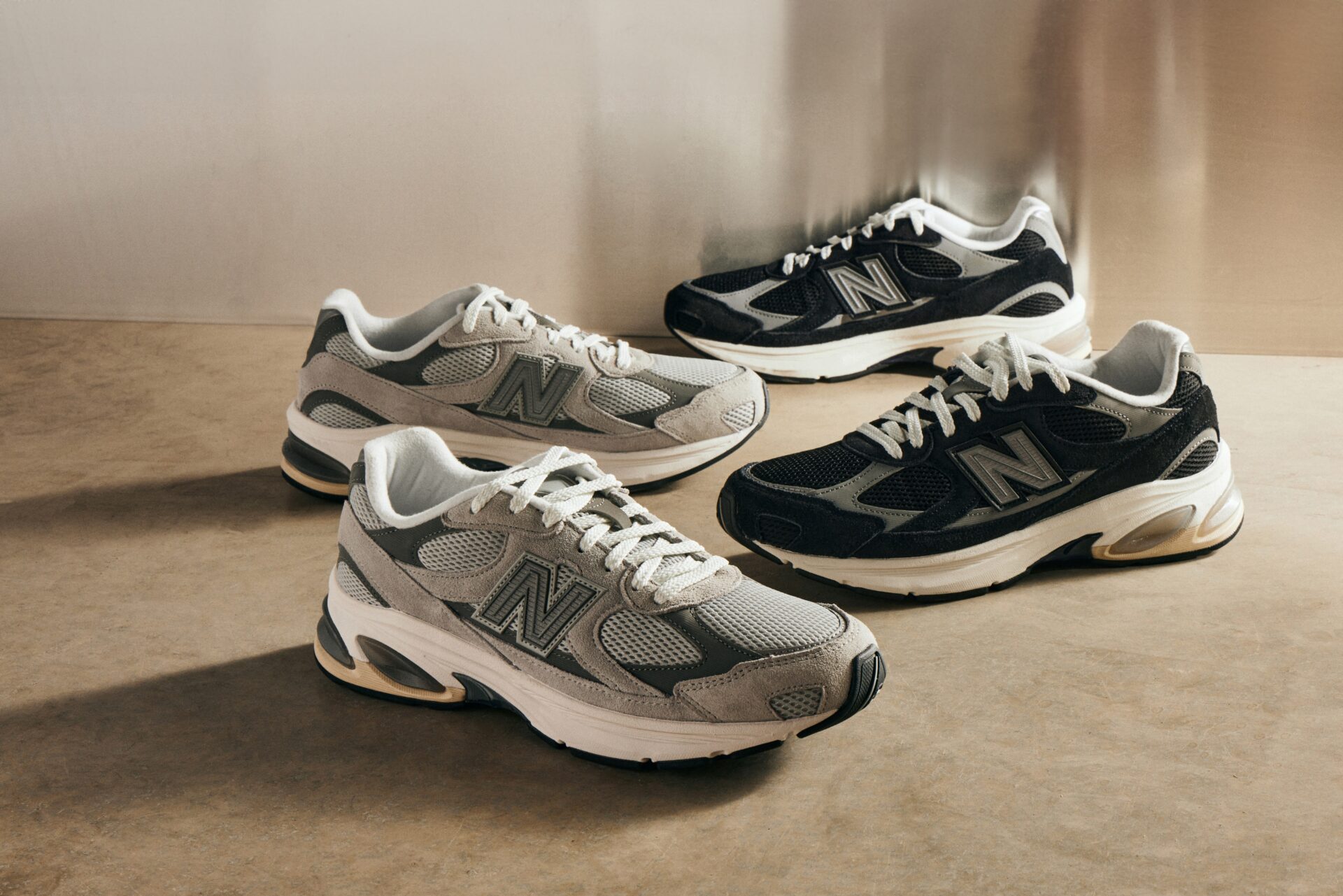 Two pairs of suede New Balance 2002R trainers, one grey and one navy.